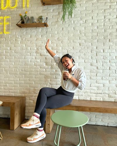 Happy YLS staff member sitting on bench with a drink in hand