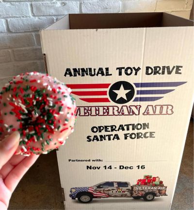 Pink donut with rainbow sprinkles next to Veteran Air toy drive donation box