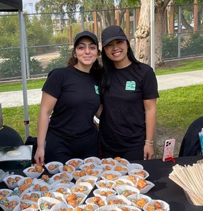 Two YLS staff members posing with pastries at community event
