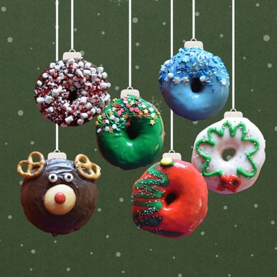 Various seasonal glazed donuts hanging from strings against a green backdrop